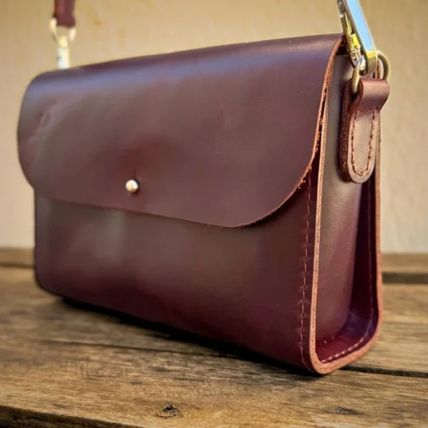 Bolsa transversal Verona Caribu em couro legítimo pinhão gold com fechamento em pino metálico e logotipo timbrado.