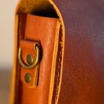 etalhe da costura e metais em latão da bolsa Parruá em couro legítimo
